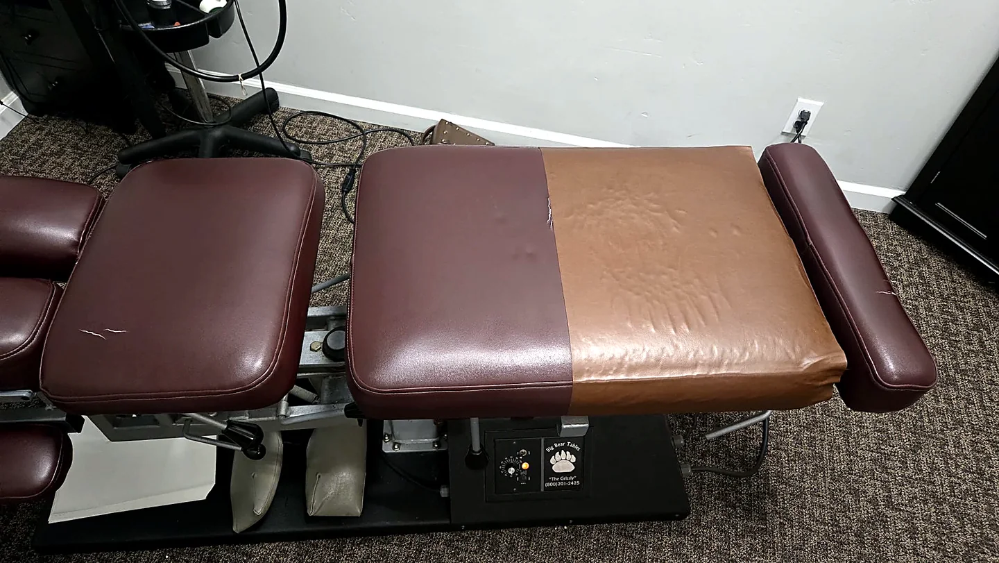 Chiropractic table with worn upholstery before repair in San Diego