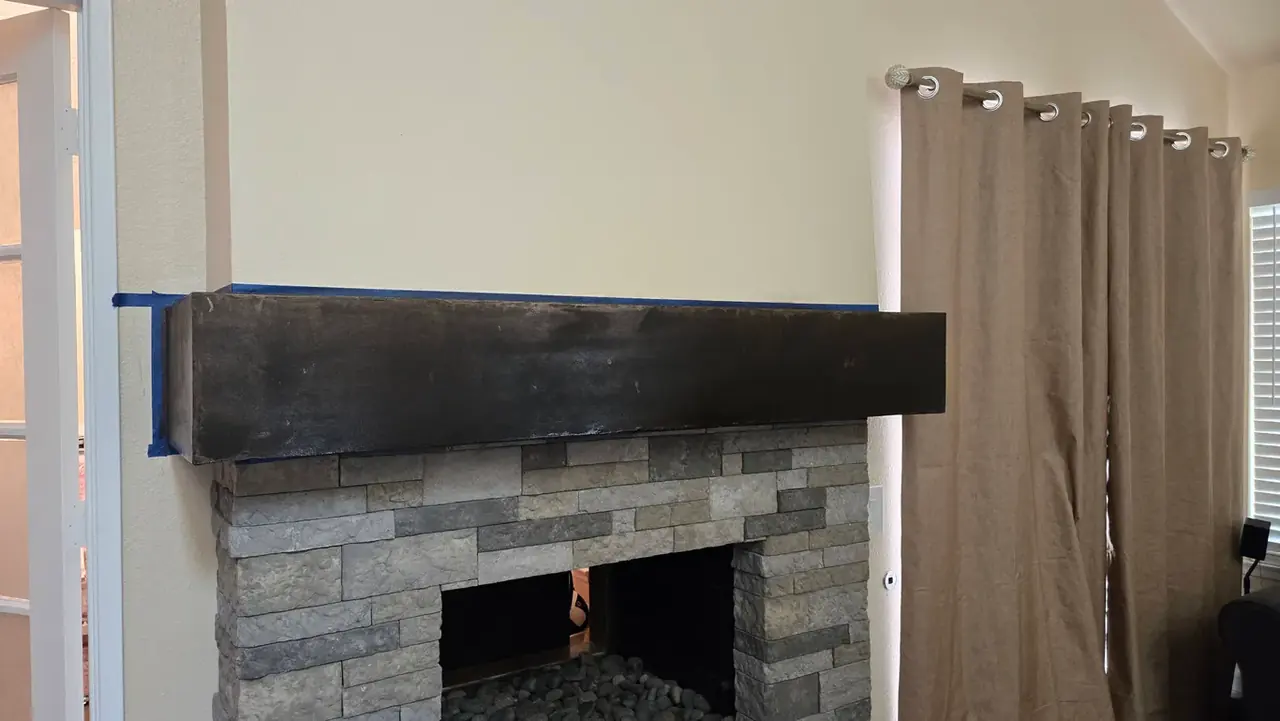 Stone fireplace with a custom wood mantel installed in San Diego
