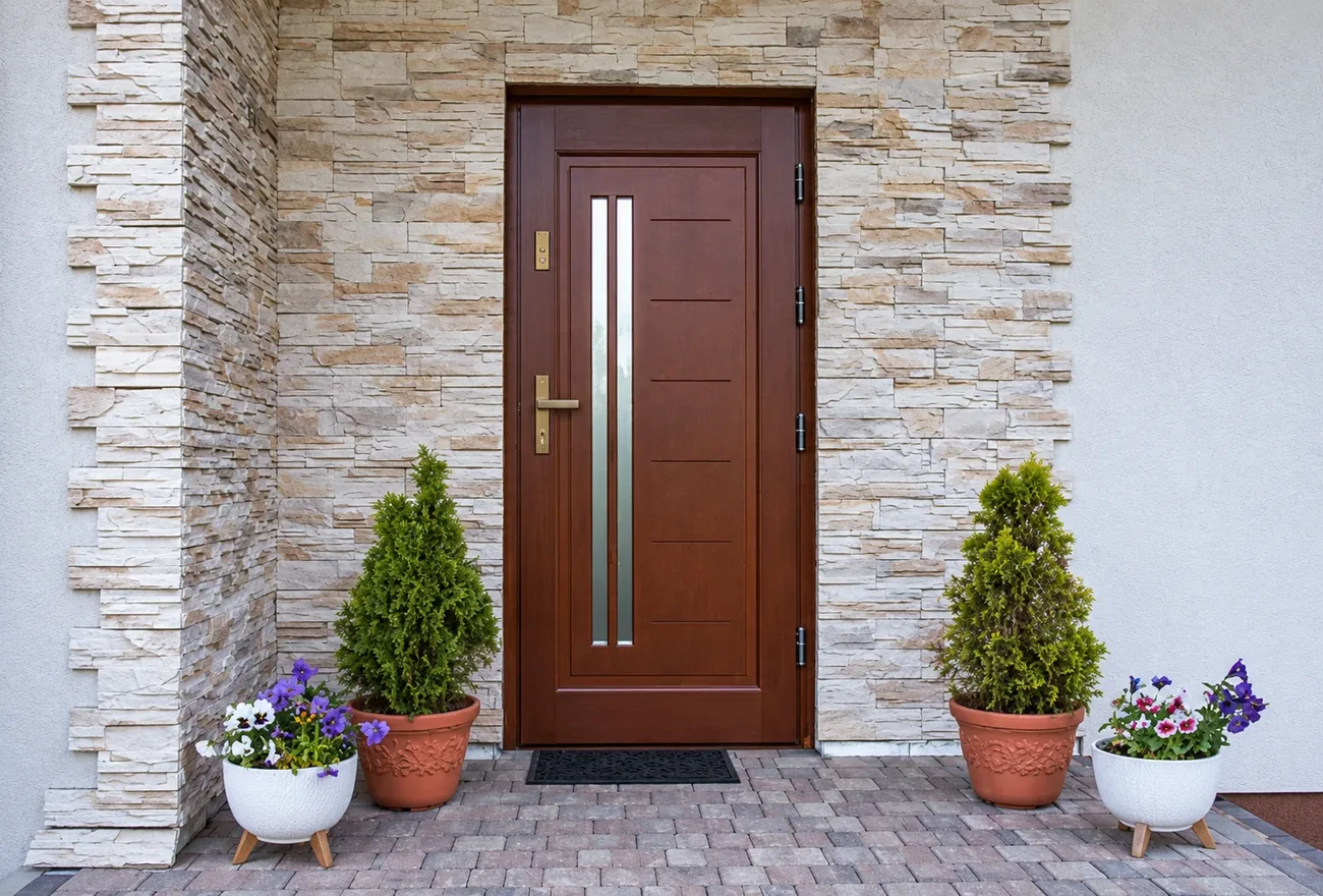 Cherry-stained front door with a frosted glass panel set in a stone entry, refinished by AllPro AG in San Diego